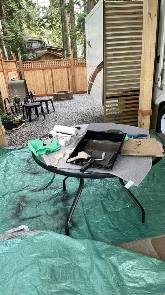 Ranch patio painting prep with paint tray, brushes, rollers, tarp, and outdoor table before patio cover makeover